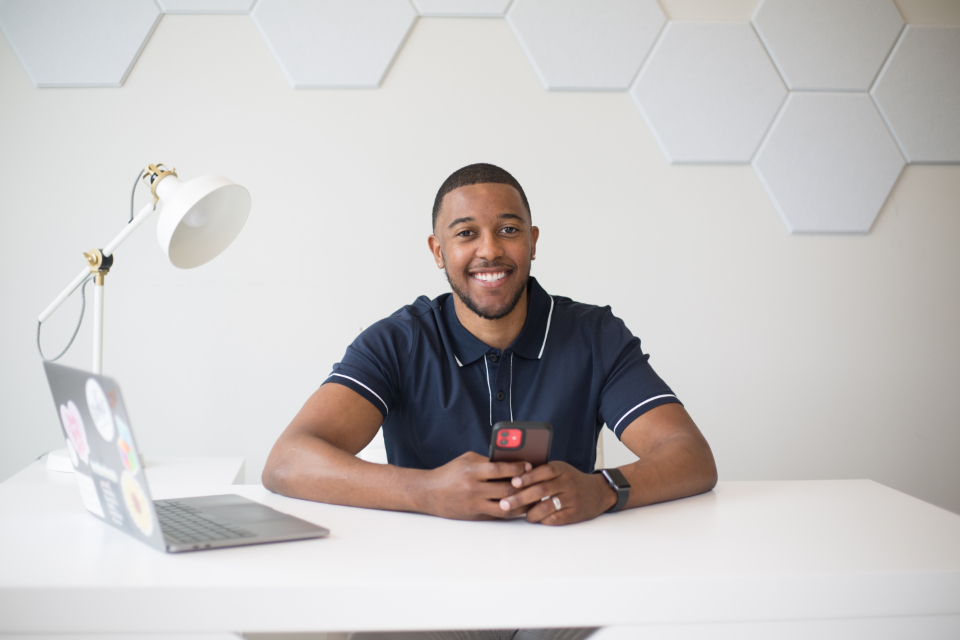 Jeune homme souriant à son bureau devant son ordinateur
